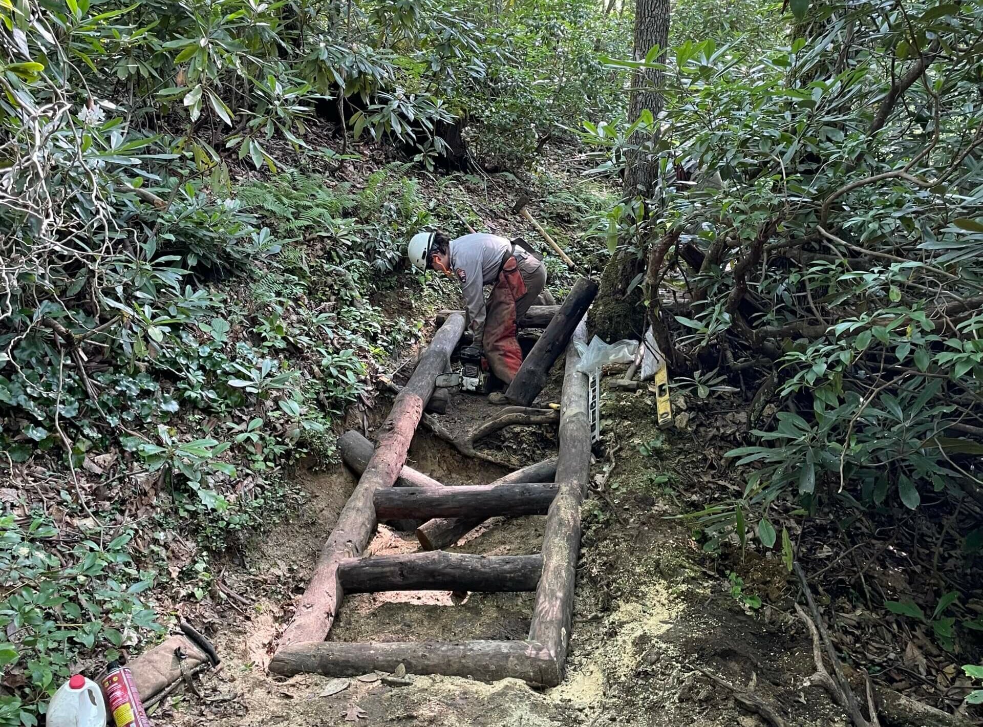 Trails Forever crew member builds log stairs on Ramsey Cascades Trail