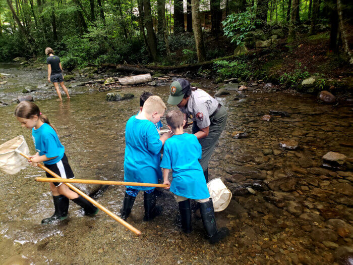 ranger helps kids use nets in stream