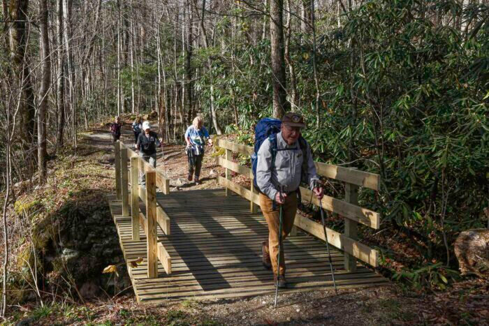 hikers walk across wood bridge