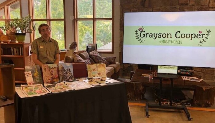 Grayson Cooper stands at a table of artwork in the Oconaluftee Visitor Center in Great Smoky Mountains National Park.