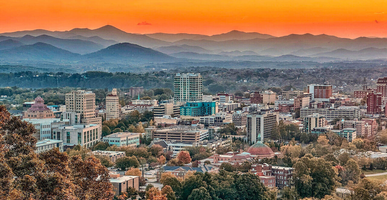 Downtown Asheville skyline at sunset with the Blue Ridge Mountains in the background